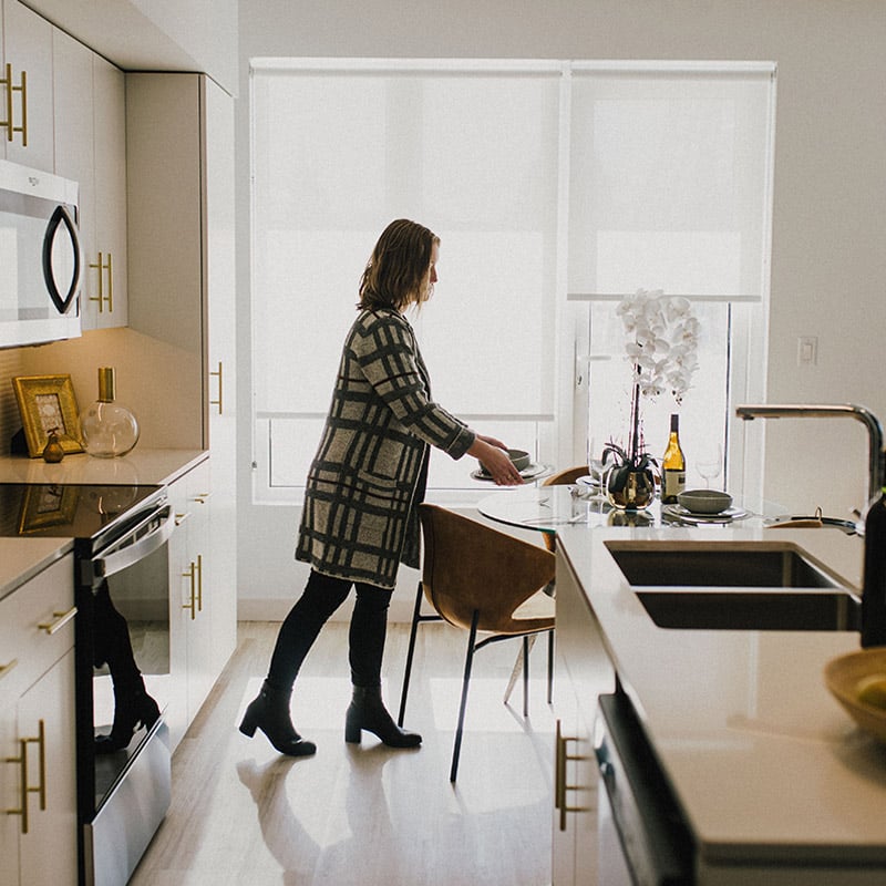 A person setting dishes at a kitchen table