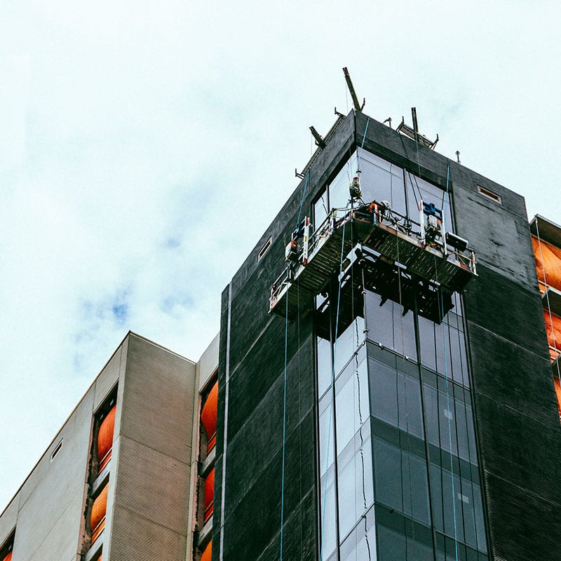 A crew of workers building on the side of a high rise