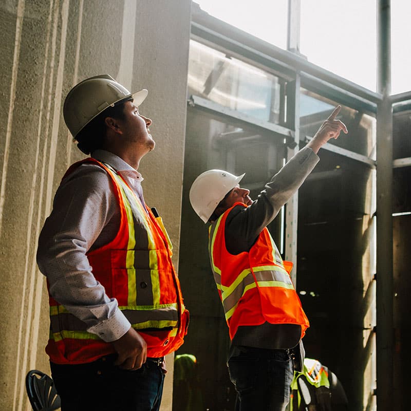 Two individuals assessing construction at an active job site